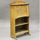 An Edwardian Arts and Crafts oak student's bureau, the fall-flap above open shelves, height 122cm,