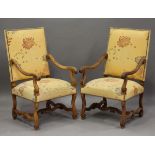 A pair of early 20th century French walnut framed armchairs, the seats and backs upholstered in a