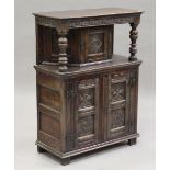 A 20th century Jacobean Revival oak side cupboard, fitted with three carved doors, height 112cm,