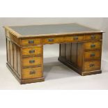 An early 20th century oak partners desk, the top inset with black leather above an arrangement of