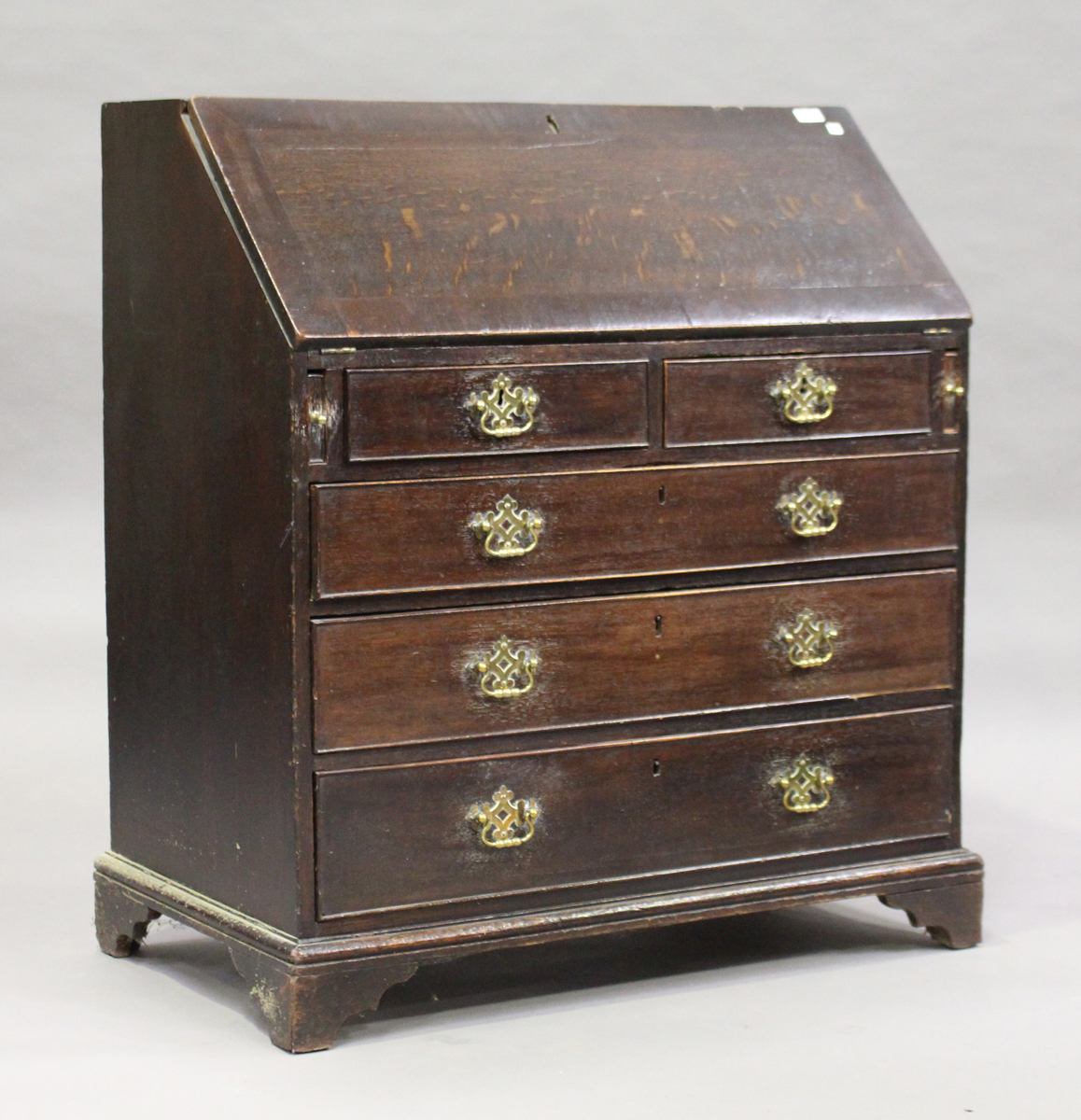 A George III oak bureau, the fall-flap above two short and three long drawers, on bracket feet,