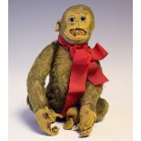 An early/mid-20th century straw-filled mohair soft toy seated monkey with black and white eyes and