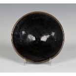 A tenmoku glazed studio pottery bowl, probably by Richard Batterham, of flared circular shape on a