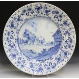 A large Delft charger, early 20th century, painted in blue with a view of a small village within a