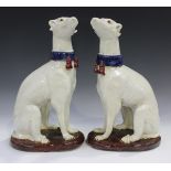 A large pair of Continental pottery greyhounds, 20th century, the white animals with blue collars