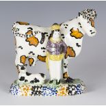 A Yorkshire Prattware cow and cowman group, circa 1800-20, the standing cow with ochre patches