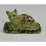 A red clay pottery model of a cat, probably 19th century, modelled recumbent on a rectangular