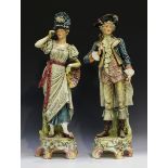 A large pair of Continental pottery figures, circa 1900, modelled in period dress on floral