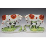 A pair of Staffordshire pottery cow and calf groups, late 19th century, modelled crossing a stream