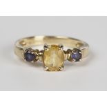 A 9ct gold, yellow and blue gem stone set three stone ring, claw set with the oval cut yellow gem