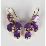 A pair of gold and amethyst four stone pendant earrings, each claw set with four oval cut amethysts,