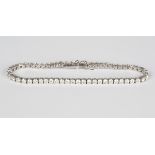 A 18ct white gold and diamond bracelet, claw set with a row of circular cut diamonds, on a snap