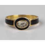 A George IV gold and black enamelled mourning ring, glazed with an oval locket compartment within