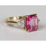 A 9ct gold ring, claw set with a rectangular step cut pink tourmaline between colourless gem set