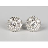 A pair of diamond cluster earrings, each claw set with the principal circular cut diamond within a