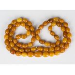 A single row necklace of sixty-eight slightly graduated oval vari-coloured mottled butterscotch