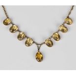 A gold and citrine necklace, the front claw set with a row of nine oval cut citrines, on a