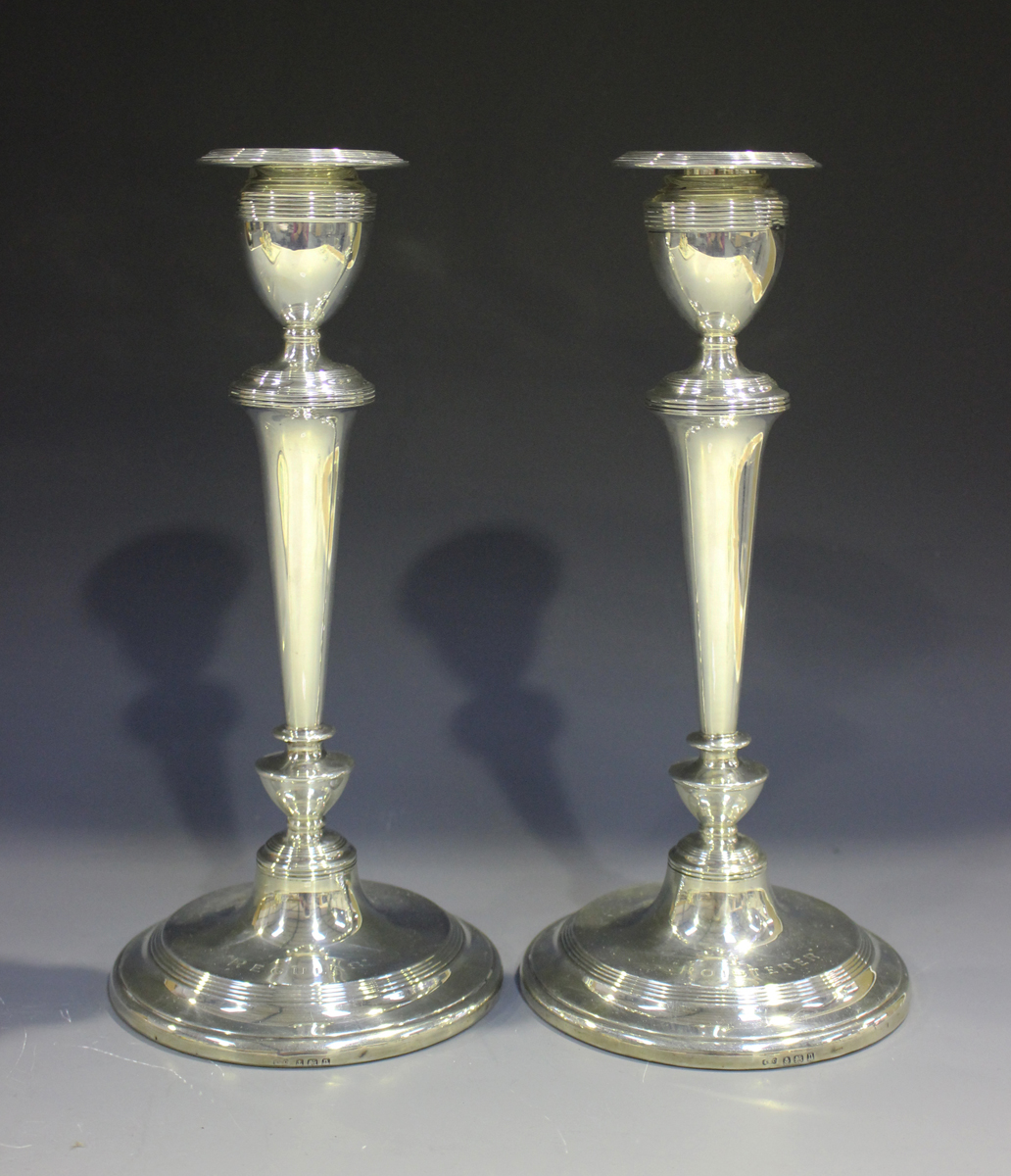 A pair of George V silver candlesticks, each with a detachable reeded nozzle above a reeded sconce