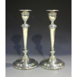 A pair of George V silver candlesticks, each with a detachable reeded nozzle above a reeded sconce
