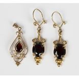 A pair of gold and garnet single stone pendant earrings, each claw set with an oval cut garnet, with
