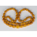 A single row necklace of fifty-one graduated oval vari-coloured butterscotch coloured semi-