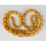 A single row necklace of fifty-six graduated oval vari-coloured mottled butterscotch coloured semi-