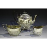 An Edwardian silver oval half-reeded three-piece tea set, comprising teapot, two-handled sugar