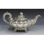 A William IV silver teapot of compressed melon form with scroll moulded spout and handle, the hinged