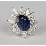 A sapphire and diamond ring, claw set with the oval cut sapphire within a surround of twelve