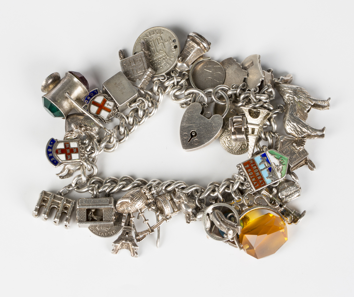 A silver curblink charm bracelet, fitted with a variety of mostly silver charms, including the