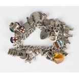 A silver curblink charm bracelet, fitted with a variety of mostly silver charms, including the