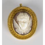 A gold mounted oval shell cameo pendant brooch, carved as an amorino, the surround with applied bead