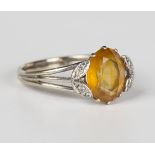 An 18ct white gold ring, claw set with an oval cut citrine between diamond set foliate shoulders,