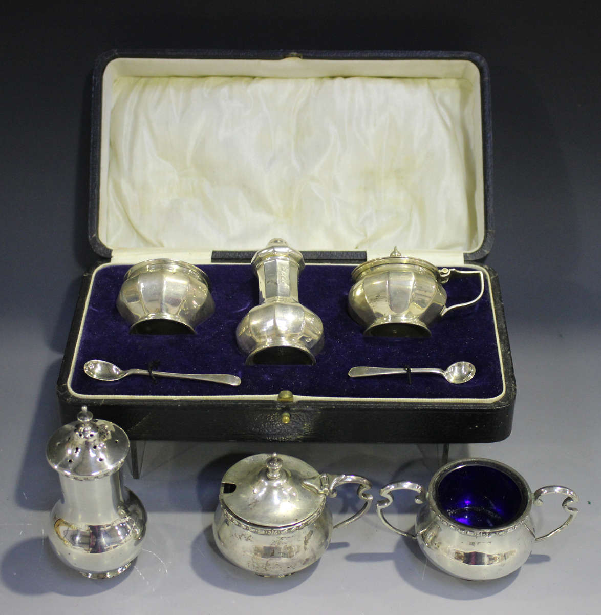 A George V silver three-piece condiment set of faceted baluster form, comprising salt, pepper caster