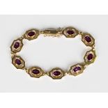 A gold and garnet bracelet, each openwork link centred by a collet set oval cut garnet, on a snap
