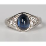 A platinum, sapphire and diamond ring, mounted with an oval cabochon sapphire between diamond set