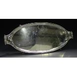 A George VI silver oval tray with beaded rim and leaf scroll handles, raised on scroll feet,