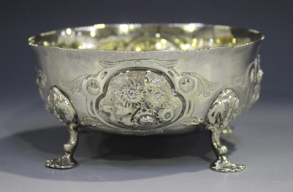 A Victorian silver circular bowl, decorated in relief with floral panels, raised on scroll legs