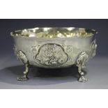 A Victorian silver circular bowl, decorated in relief with floral panels, raised on scroll legs