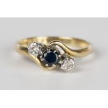 An 18ct gold, sapphire and diamond three stone ring, claw set with a circular cut sapphire between