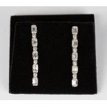 A pair of white gold and diamond pendant earrings, each mounted with a row of baguette and