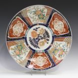 A Japanese Imari porcelain charger, Meiji period, decorated with alternating panels of flowers and