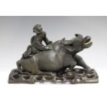 A Chinese carved hardwood figure group of a boy seated on the back of a recumbent water buffalo,