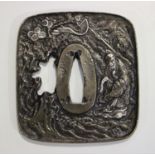 A Japanese brown patinated bronze tsuba with silver inlaid decoration, one side cast in relief