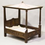 A late 20th century oak framed diminutive four-poster bed, probably made as a large doll or dog's