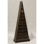 A modern hardwood nine drawer chest of triangular form, height 159cm, width 62cm, depth 25.5cm.