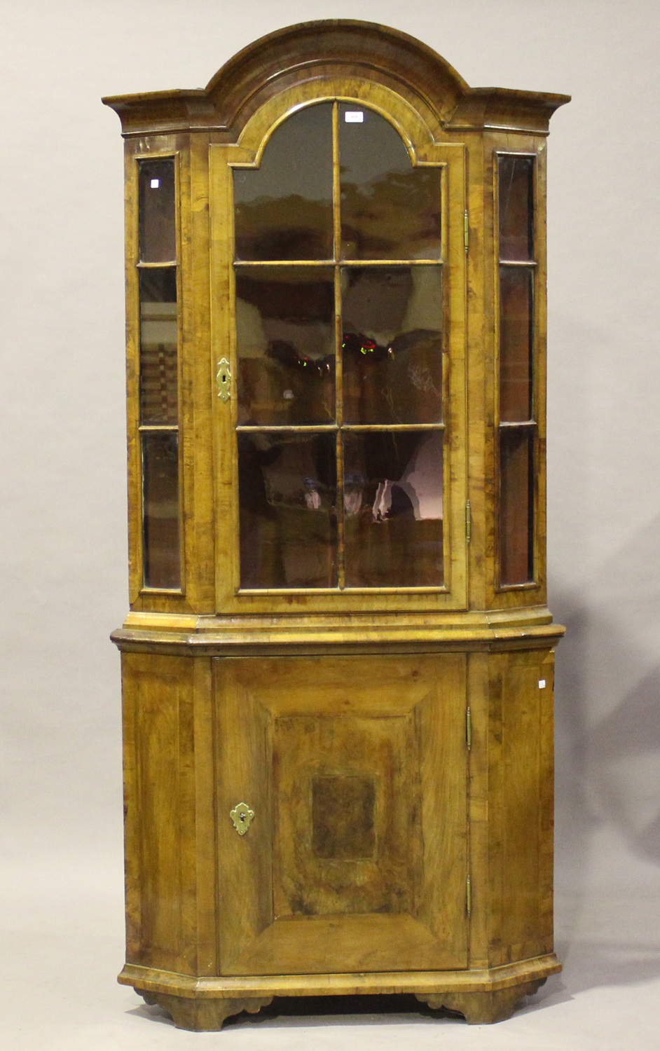 An 18th century Continental walnut floor-standing corner cabinet with an arched cavetto moulded