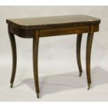 A Regency rosewood fold-over tea table with boxwood stringing, raised on sabre legs and brass