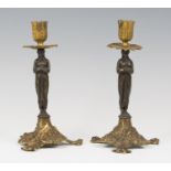A pair of 19th century brown patinated and gilt bronze figural candlesticks, the classical female