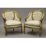 A pair of 20th century Louis XVI style giltwood showframe tub back armchairs, upholstered in foliate